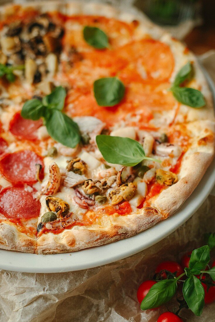 Pizza Quattro Stagioni with salami, seafood, tomatoes and mushrooms