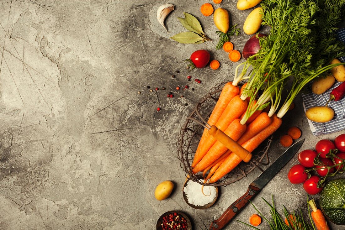 Fresh carrots bunch and vegetables on rustic grey stone background