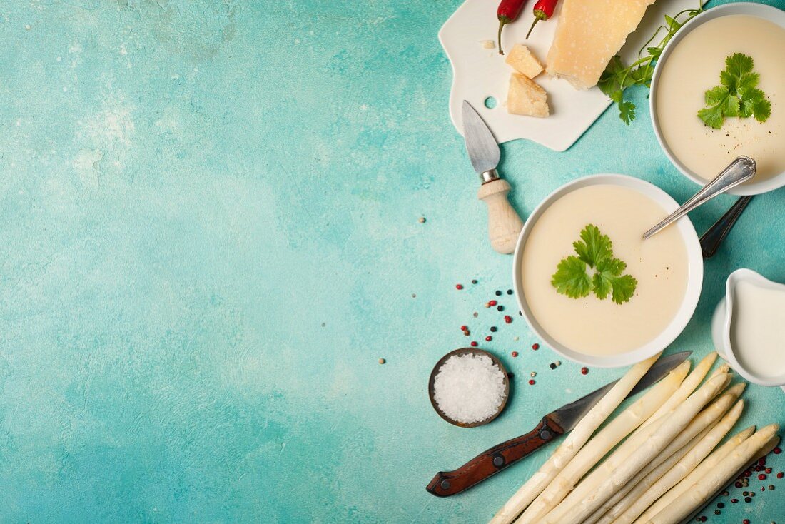 weiße Spargelcremesuppe auf blauem Hintergrund