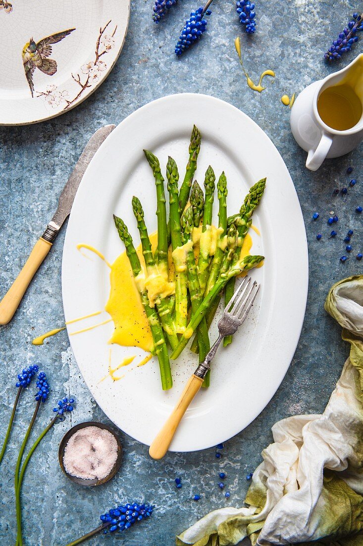 Grüner Spargel mit Sauce Hollandaise auf Servierplatte (Aufsicht)