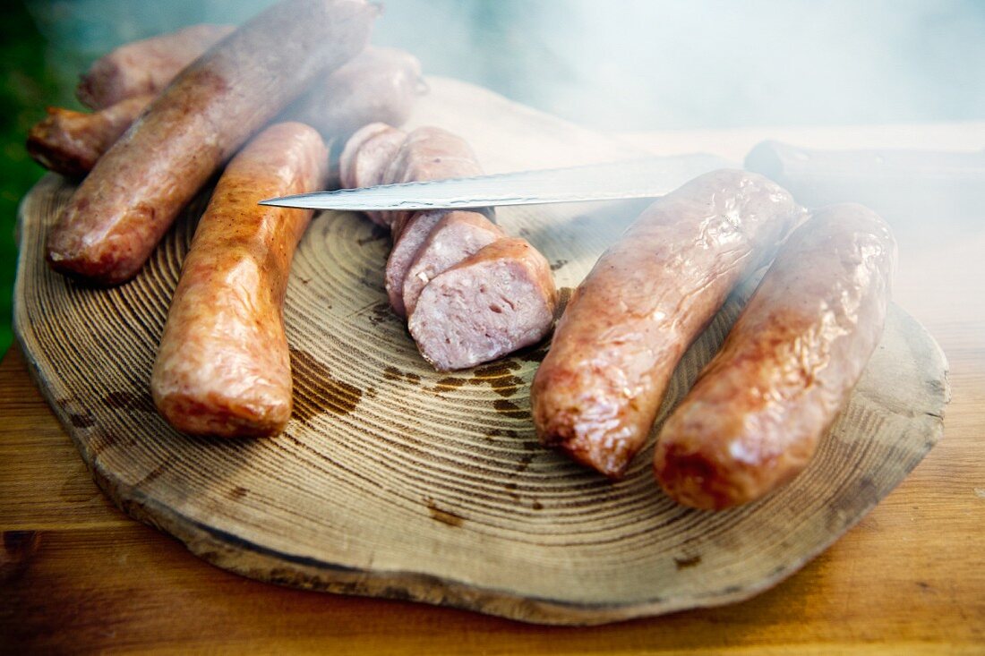 Smoked sausages with a knife on a wooden slab