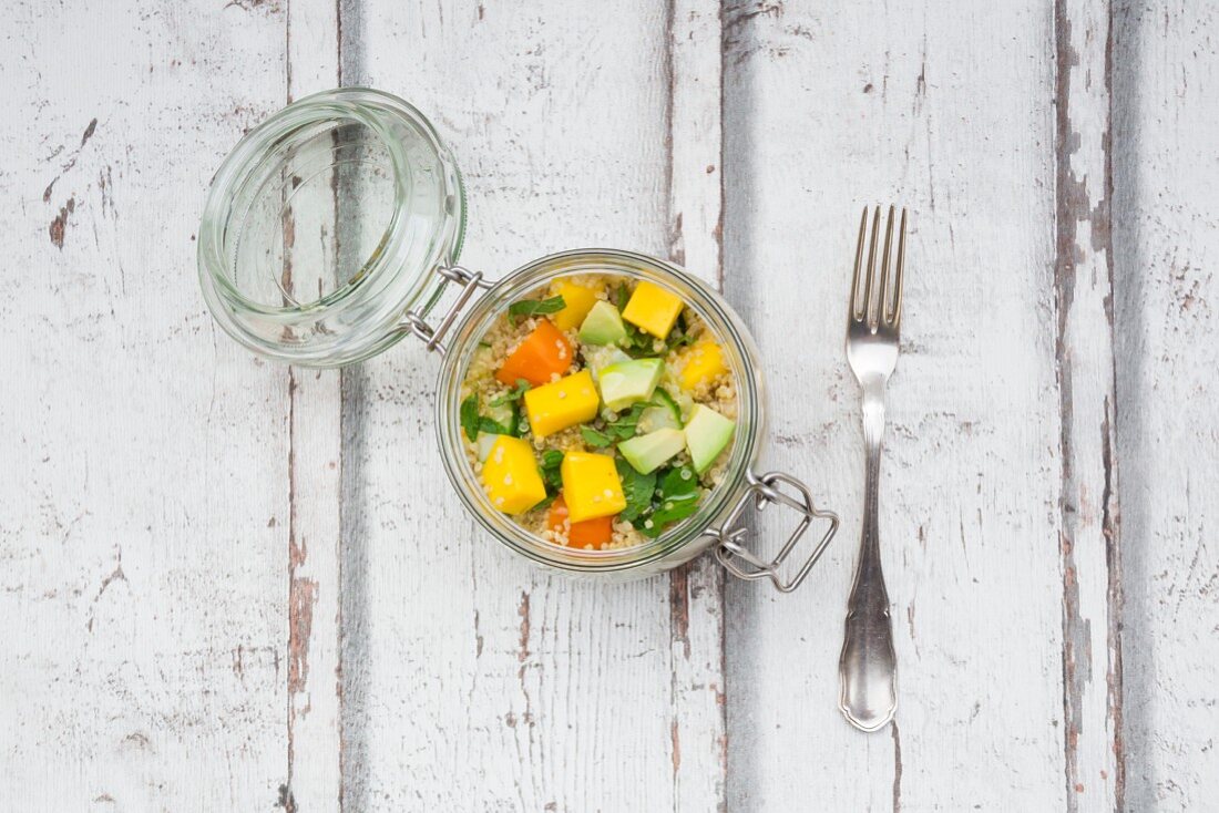 Quinoa salad with avocado, cucumber, tomato and mango in a glass jar