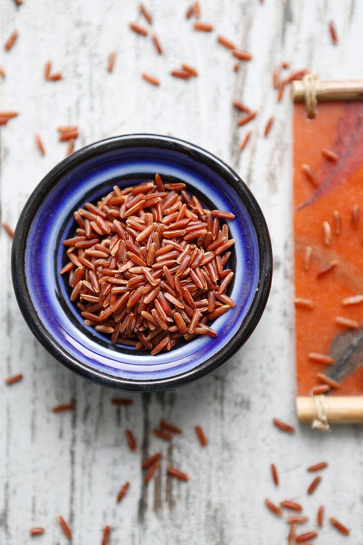 Red rice in a bowl on a colourful background (seen from above)
