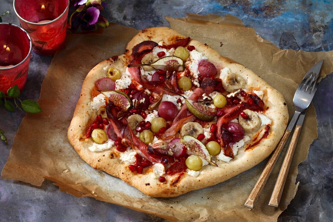 A sweet pizza with figs, grapes, banana and pomegranate seeds