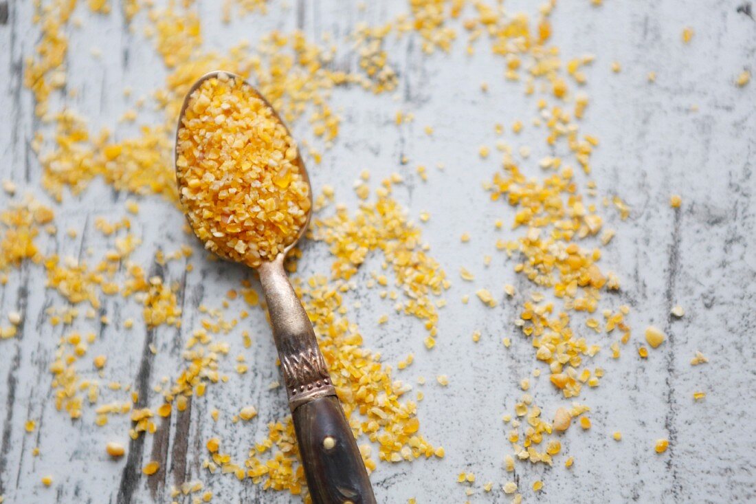 Couscous on a spoon and a wooden background