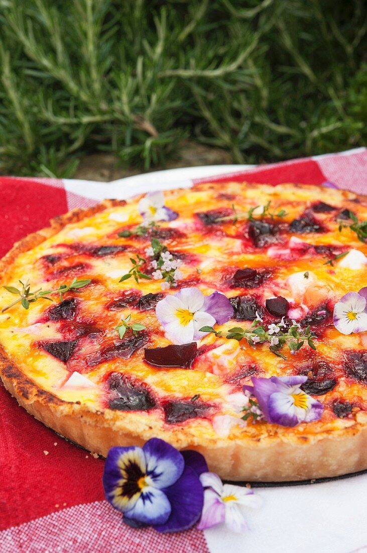 Sommerliche Rote-Bete-Quiche mit Feta und Hornveilchen auf Picknickdecke