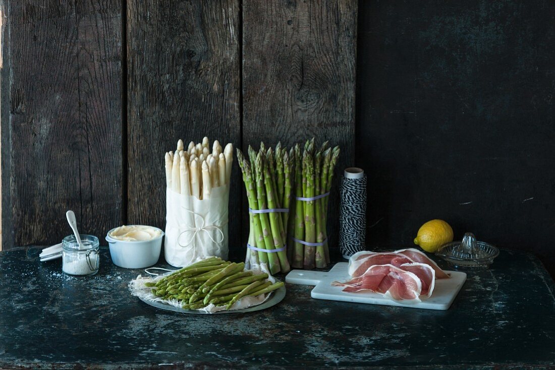 Various types of asparagus, ham, a lemon and salt