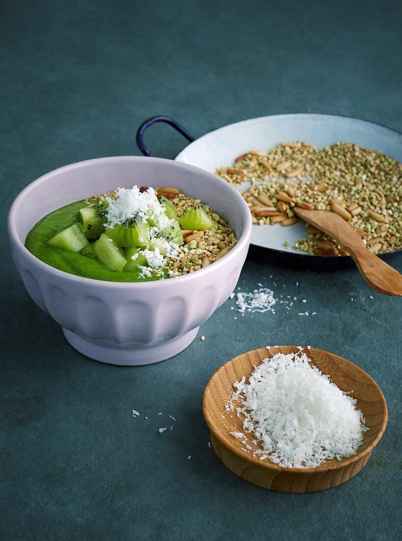 Green smoothie bowl with kiwi, matcha powder, nuts and buckwheat