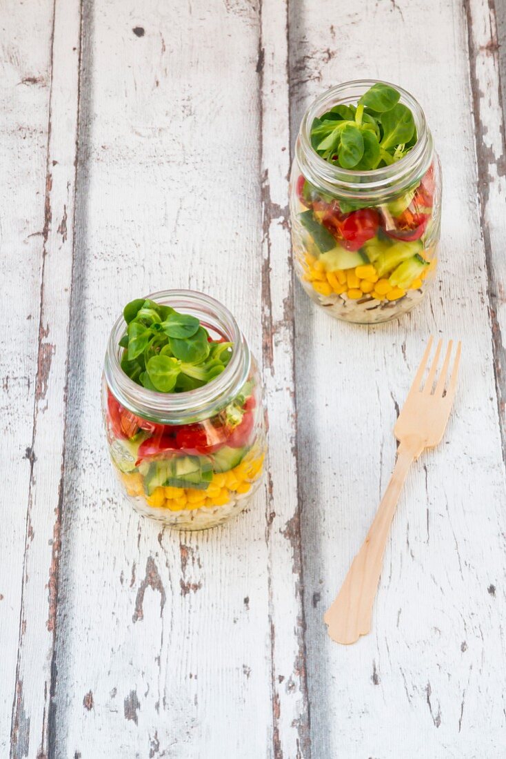 Rice salad in a glass jar with wild rice, sweetcorn, cucumber, tomato and lamb's lettuce