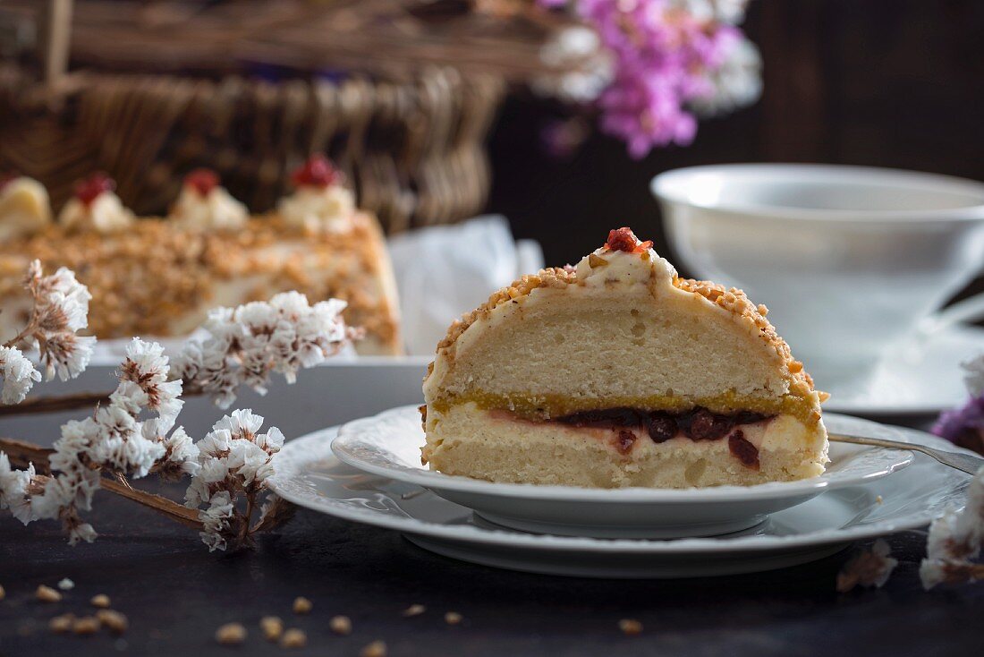 Biskuit mit Vanillecreme, Apfel-, Mango- und Preiselbeerfüllung, ummantelt mit Haselnusskrokant (vegan)