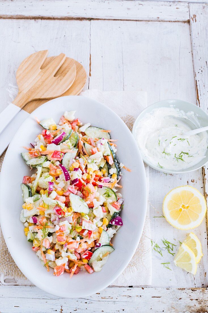 Colourful vegetable salad with yoghurt and dill dressing and lemon
