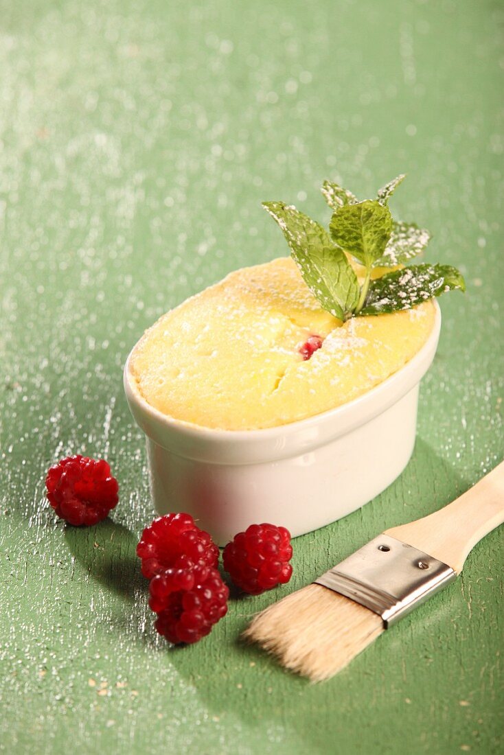 A small cheesecake in an ovenproof dish with raspberries and mint leaves