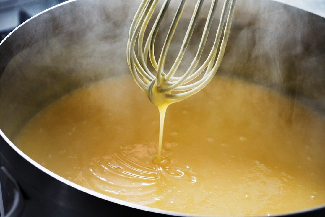 Lemon curd being stirred with a whisk