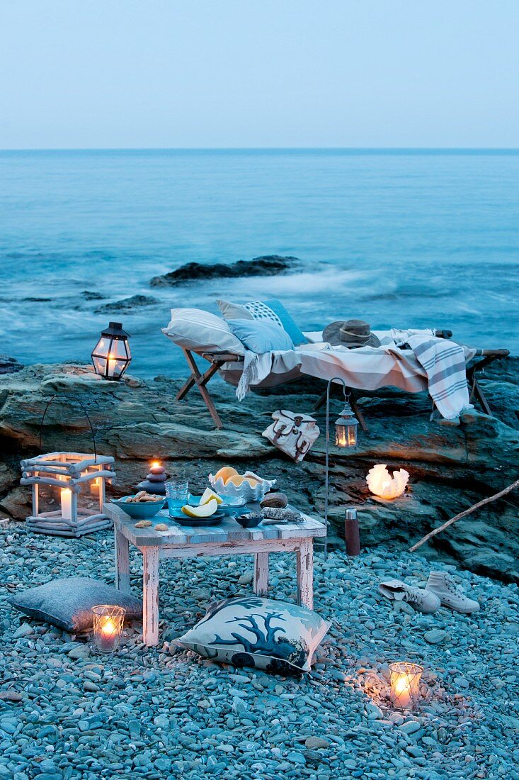 Candle lantern, lounger and cushions for romantic picnic by the sea