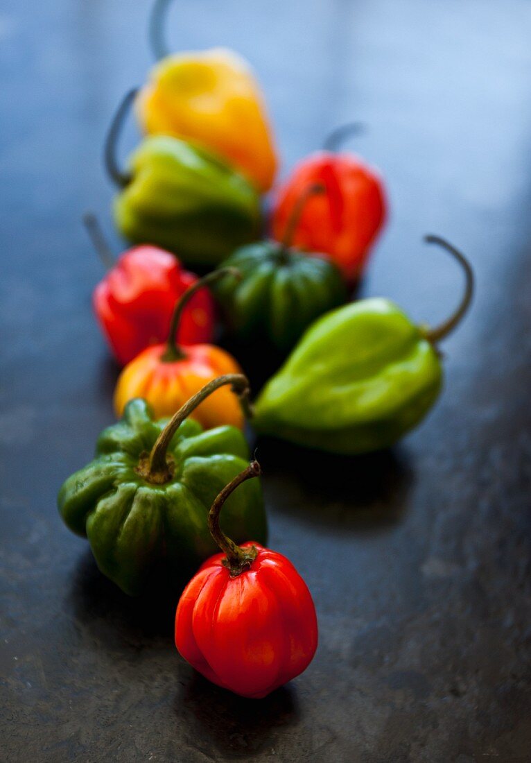 Verschiedenfarbige Chilischoten auf schwarzer Schieferplatte