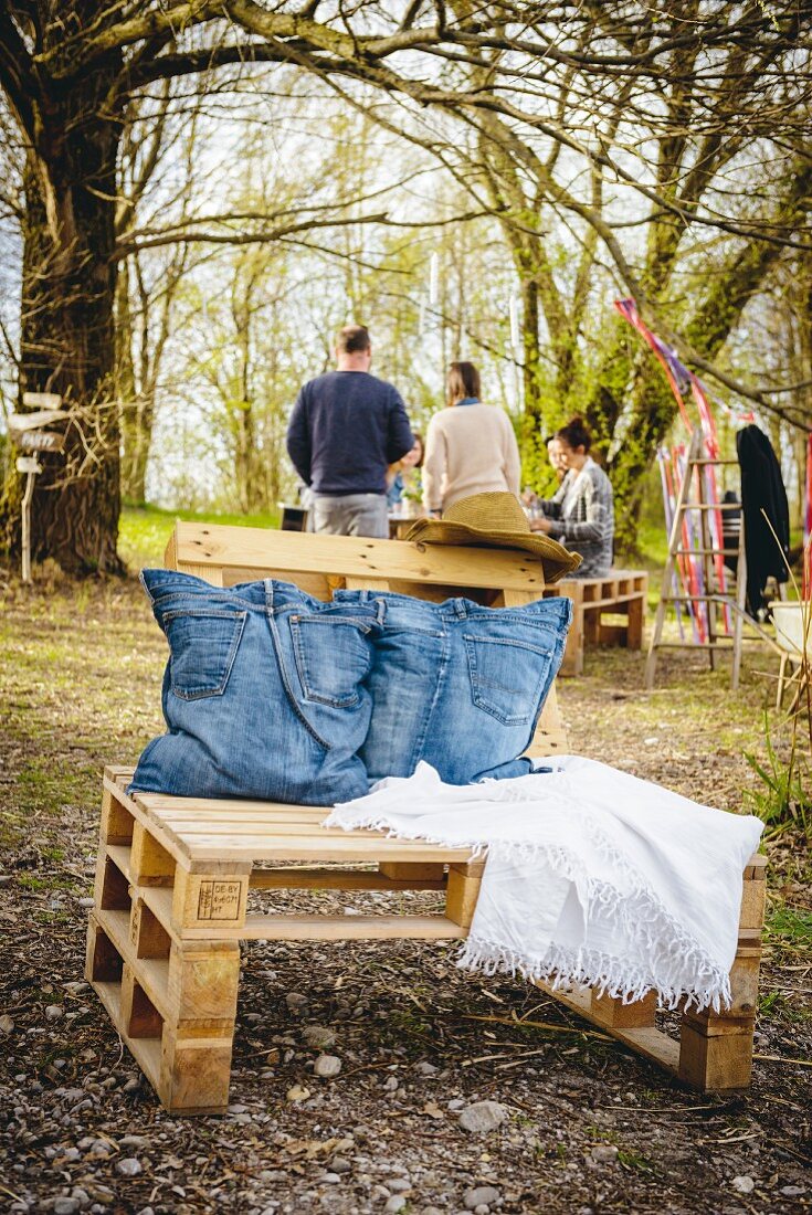 Cushions made from old jeans on chair built from pallets in garden