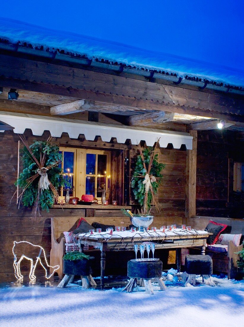 Snowy decorated chalet terrace with lighting at twilight