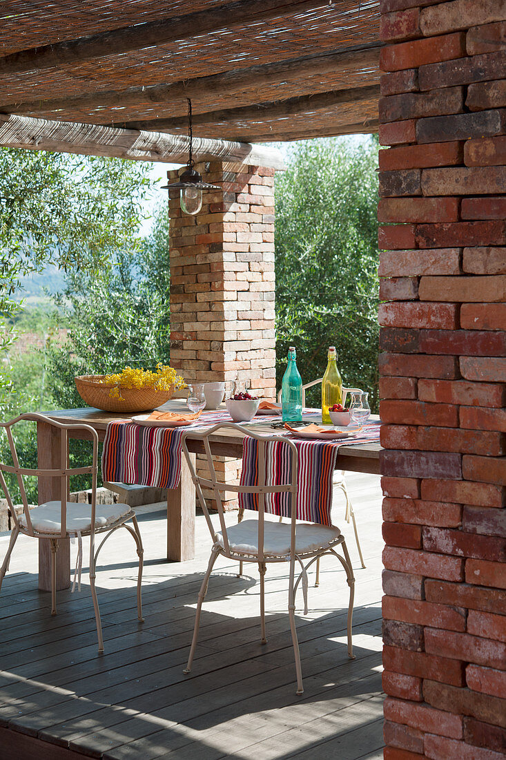 Sommerlich gedeckter Tisch auf überdachter Terrasse