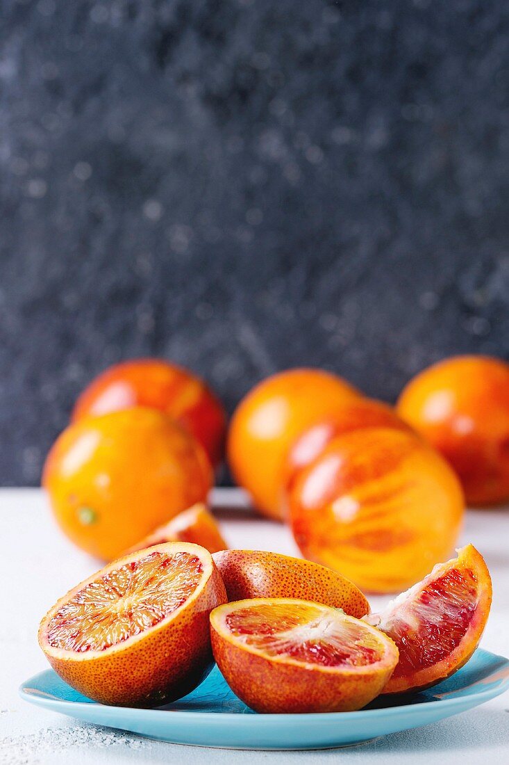 Sliced and whole ripe juicy Sicilian Blood oranges fruits on ceramic plate
