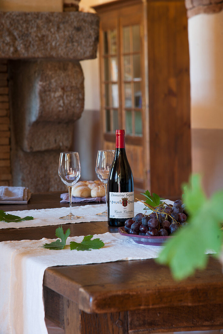 White bottle, glasses and grapes on rustic wooden table