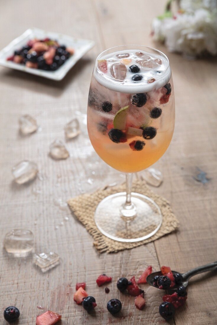White Sangria with berries in a large wine glass and ice