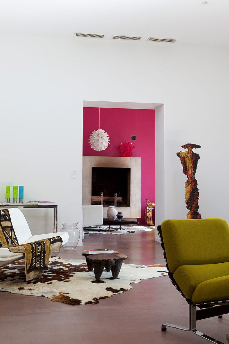 Artistic mixture of furnishings in living room and view of fireplace through open doorway