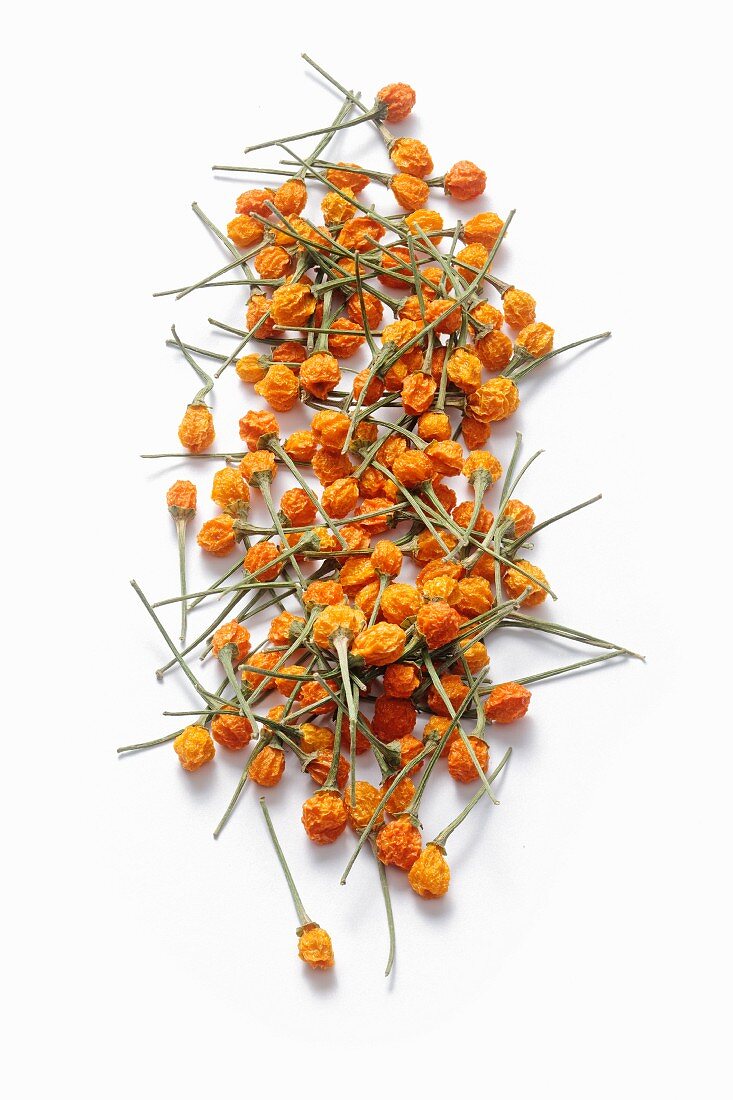 Dried yellow charapita chillies in front of a white background