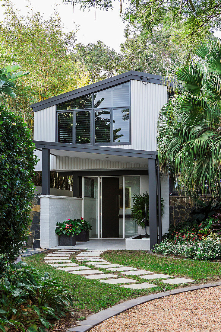 Two-storey house with a window front, in green surroundings