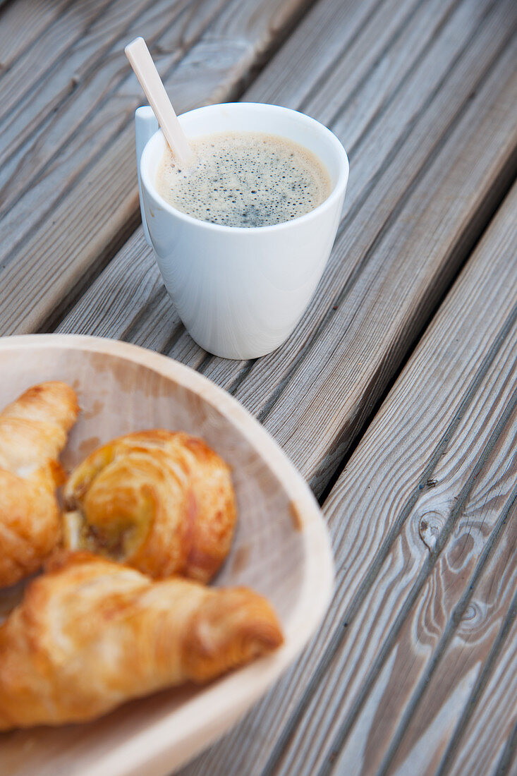 Tasse Kaffee und eine Schale mit Gebäck auf Holzbrettern