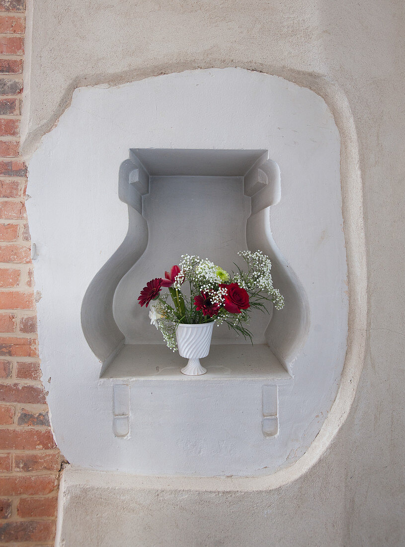 Vase of flowers in niche in wall