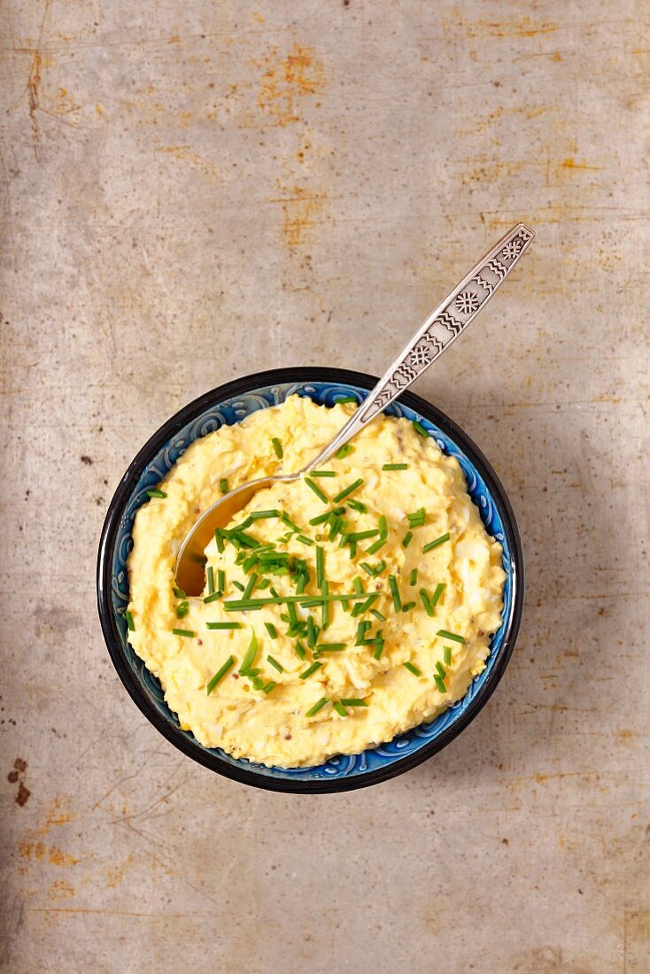 Egg dip with horseradish and chives in a small bowl on a stone background