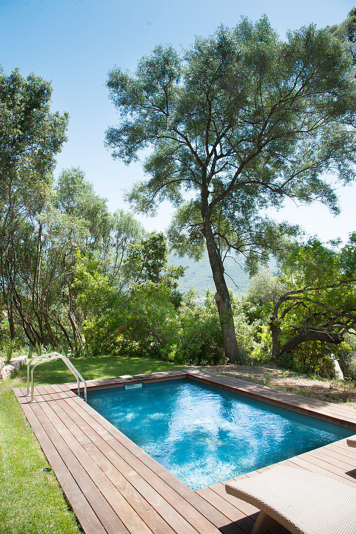 Swimming pool surrounded by wooden decking in Mediterranean garden