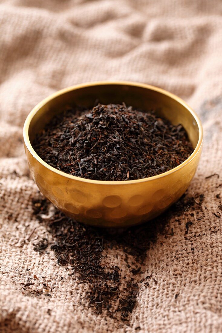 Black tea in a metal bowl on a jute cloth