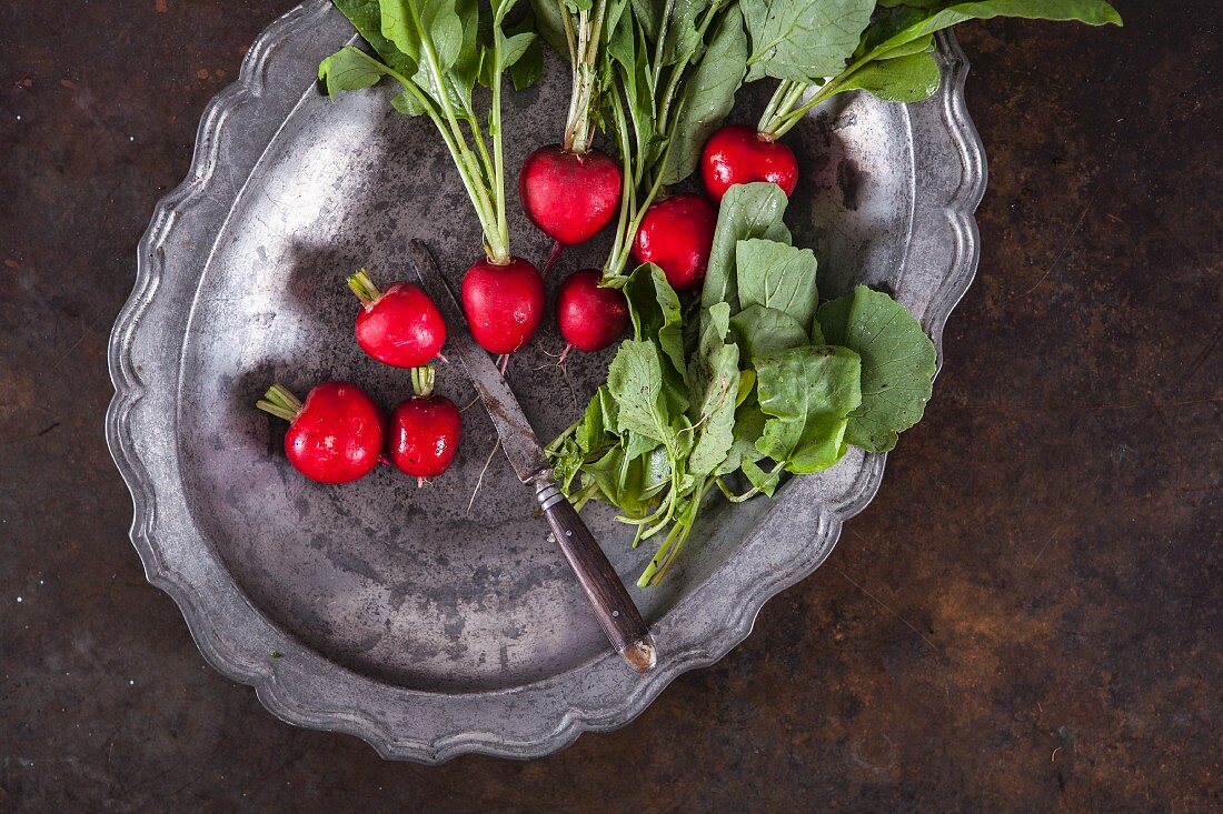 Radishes on a metal tray with a knife