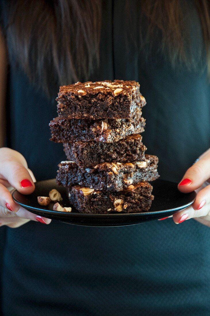 Frau hält Teller mit glutenfreien Haselnussbrownies