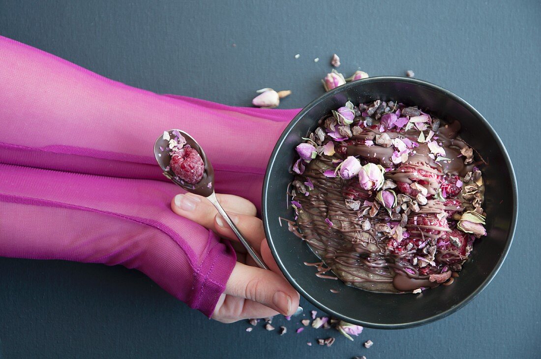 Schokoladen-Smoothie-Bowl mit Himbeeren und getrockneten Rosenknospen