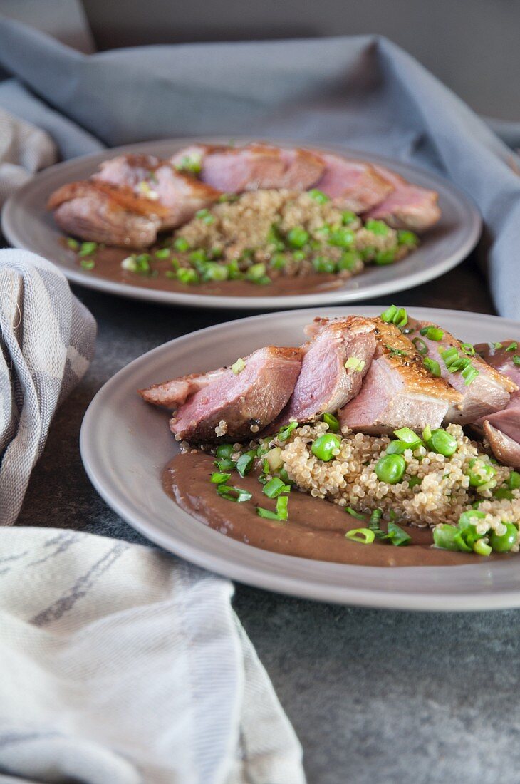 Duck breast with quinoa, a brown sauce and peas