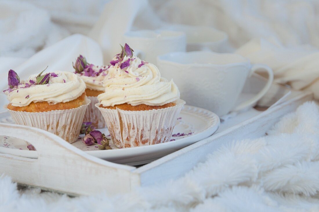 Vanille-Cupcakes mit getrockneten Rosenblüten auf weißem Tablett