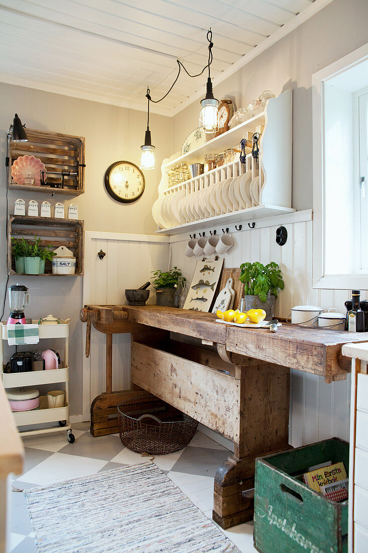Old workbench below plate rack in country-house kitchen
