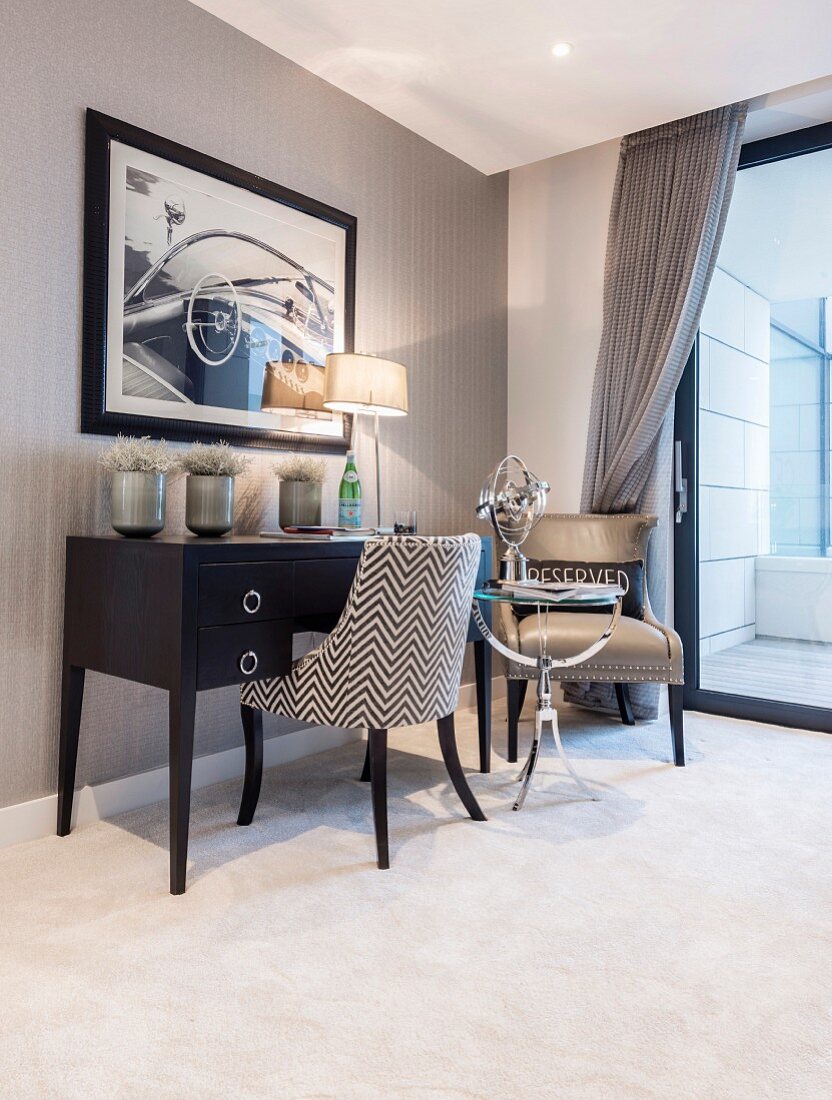 Upholstered chair, side table and armchair at elegant desk next to glass sliding door