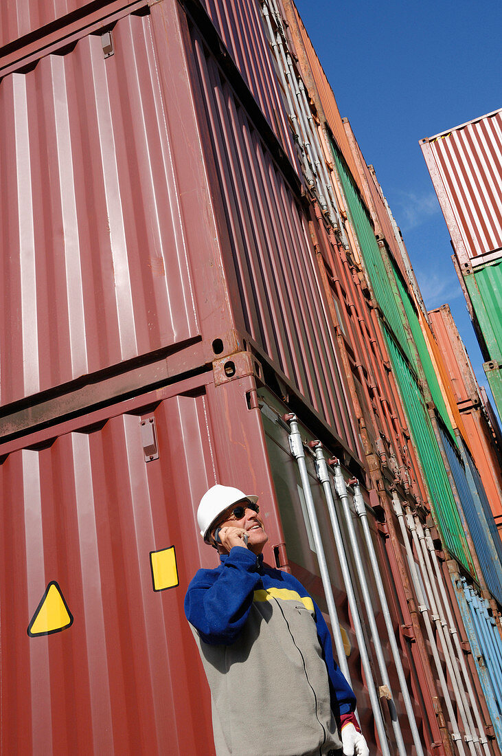 Industrial worker on cell phone with cargo containers