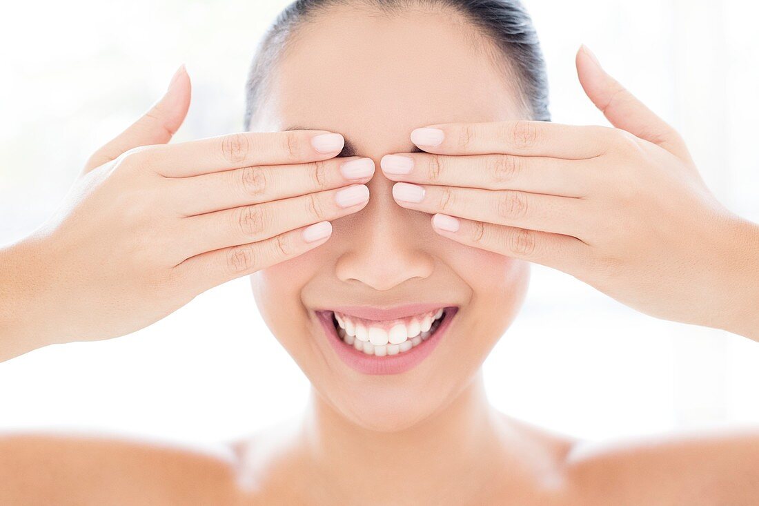 Woman with hands touching covering eyes