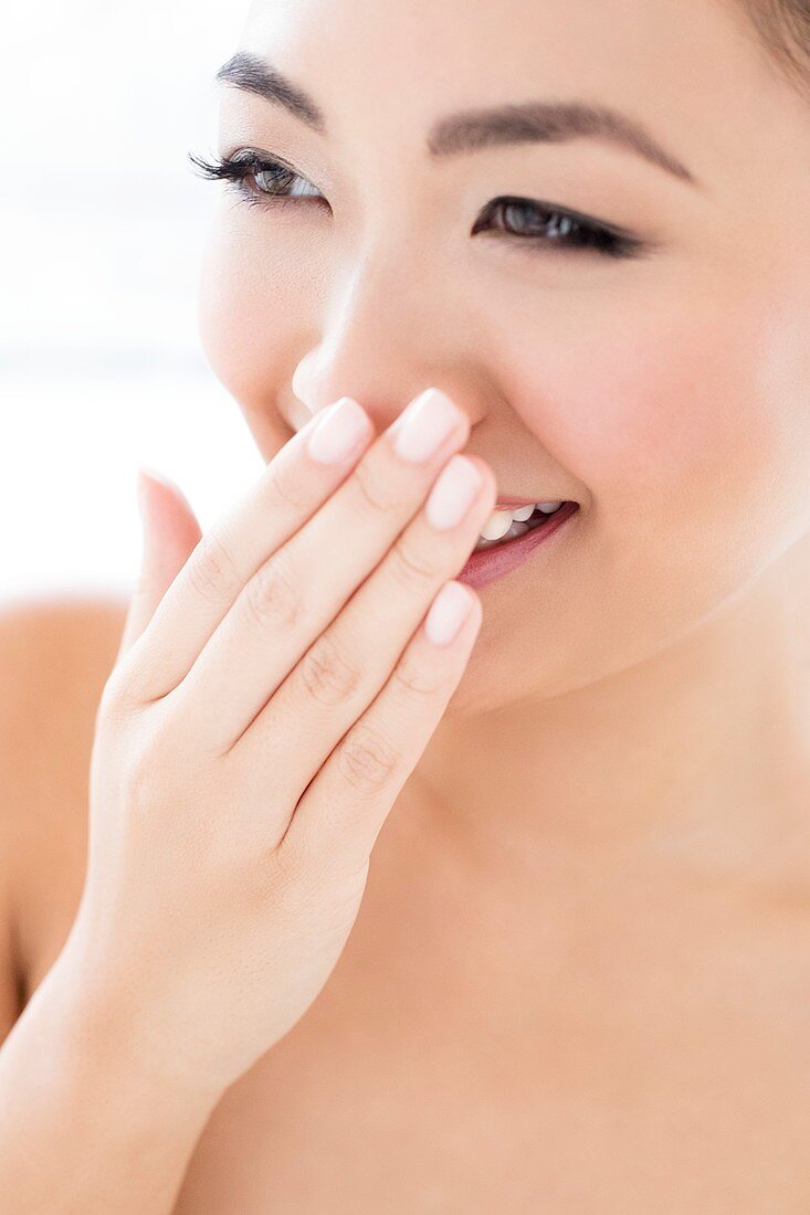 Woman laughing with hand covering mouth