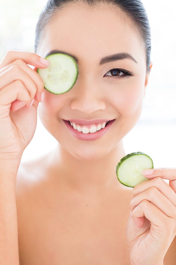 Woman holding cucumber in front of eye