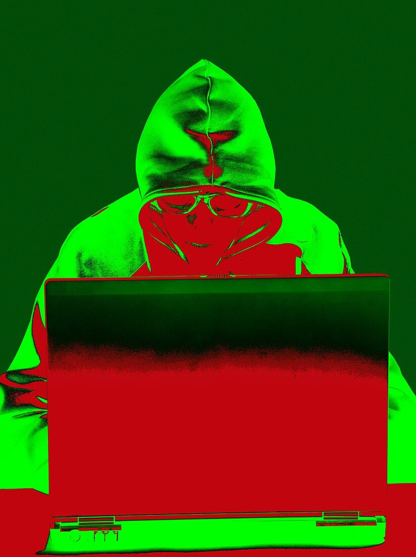 Hooded figure hacking laptop computer