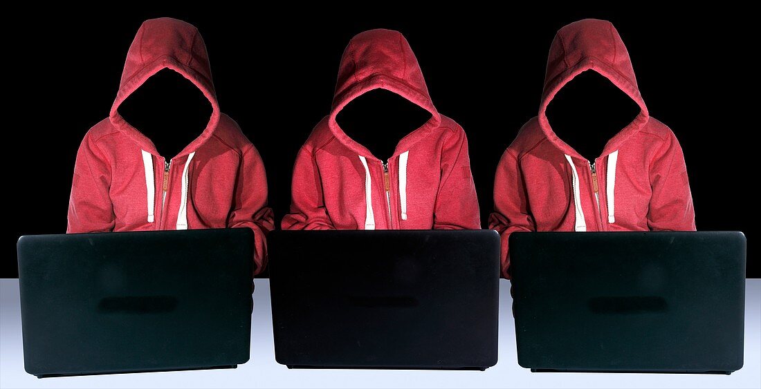 Hooded figures hacking laptop computers