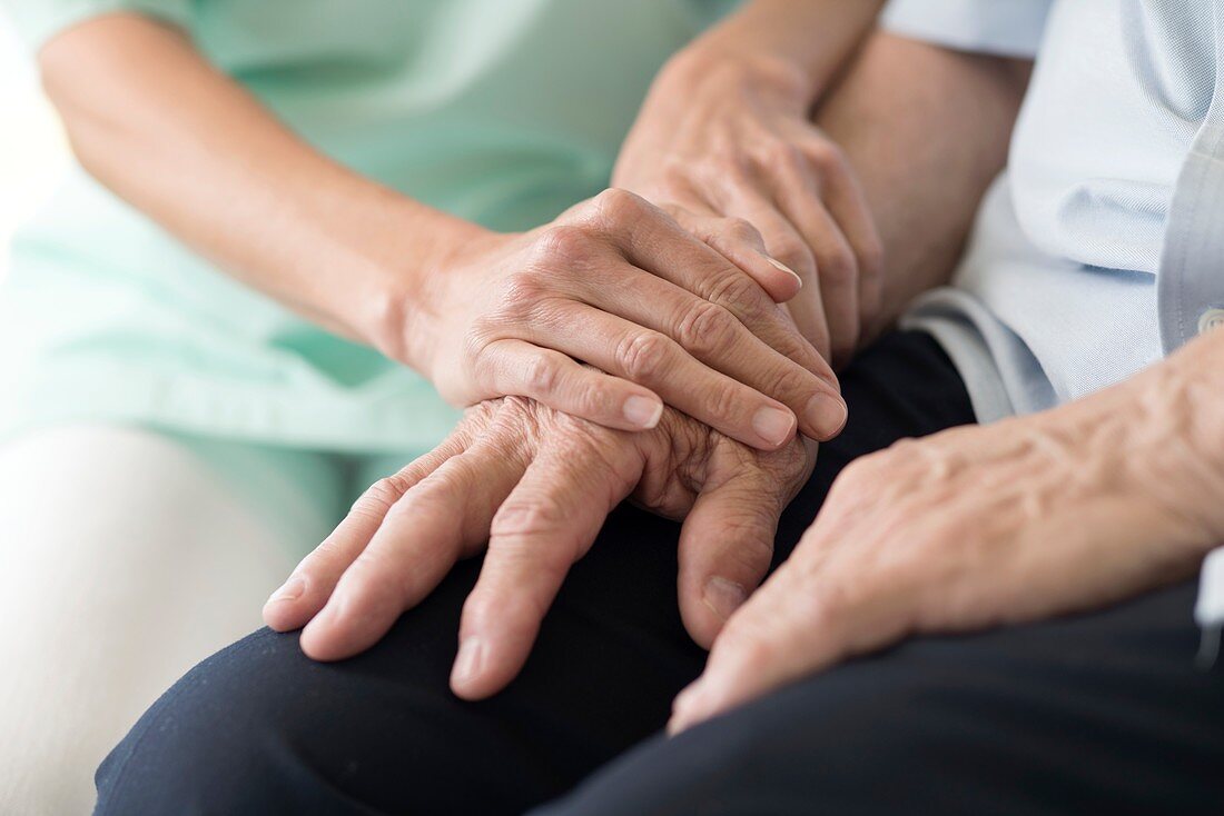 Care worker holding senior man's hands