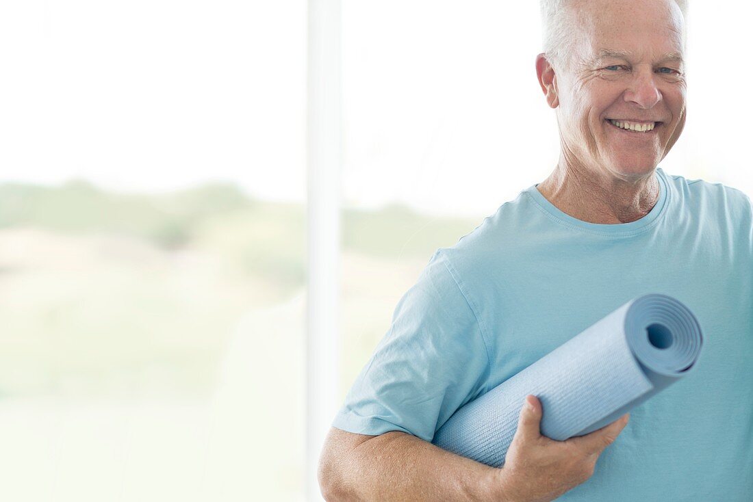 Senior man holding yoga mat