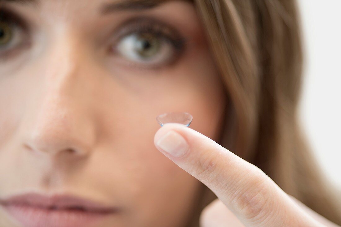 Mid adult woman with contact lens on finger