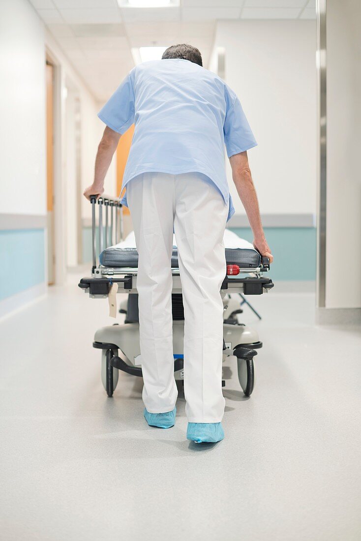 Nurse orderly pushing bed down corridor